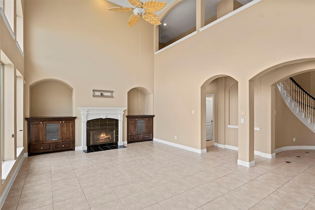 11812 Sea Shadow Bnd, Pearland, TX 77584 - unfurnished living room with light tile patterned floors, a tile fireplace, a towering ceiling, stairway, and ceiling fan