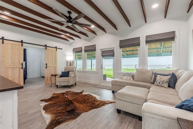 living area with beamed ceiling, a ceiling fan, light wood-style flooring, and a barn door