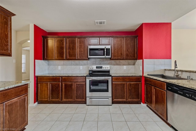 1056 Decker Dr, Fate, TX 75189 - kitchen featuring decorative backsplash, a sink, arched walkways, visible vents, and appliances with stainless steel finishes