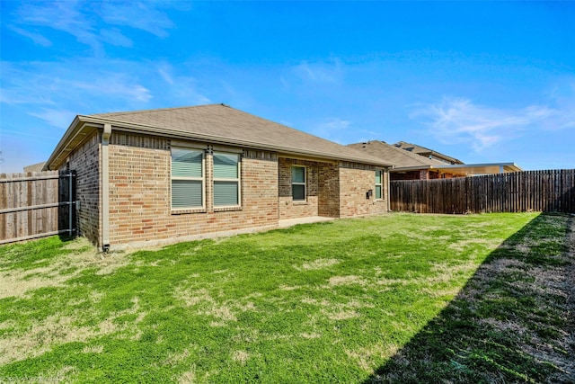 1056 Decker Dr, Fate, TX 75189 - back of house with a fenced backyard, brick siding, roof with shingles, and a lawn