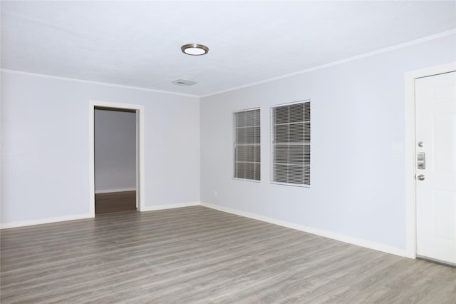 unfurnished room featuring baseboards, wood finished floors, and crown molding