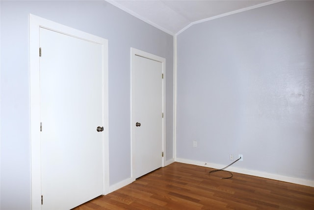 unfurnished bedroom featuring baseboards, wood finished floors, crown molding, and vaulted ceiling