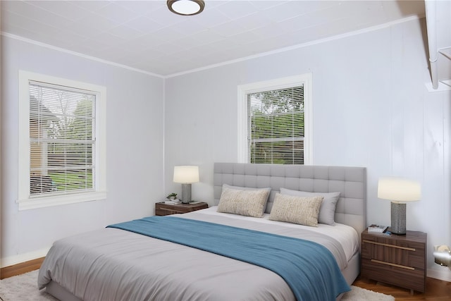 bedroom with ornamental molding, wood finished floors, and baseboards