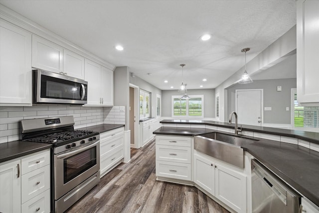 1613 Willow View St, La Porte, TX 77571 - kitchen with stainless steel appliances, a sink, dark countertops, dark wood finished floors, and white cabinets