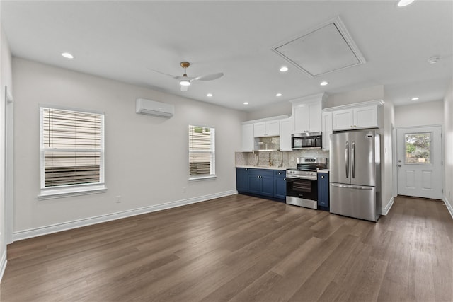 3513 Ursuline St, Galveston, TX 77550 - kitchen featuring appliances with stainless steel finishes, a wall mounted air conditioner, white cabinets, decorative backsplash, and dark wood-type flooring
