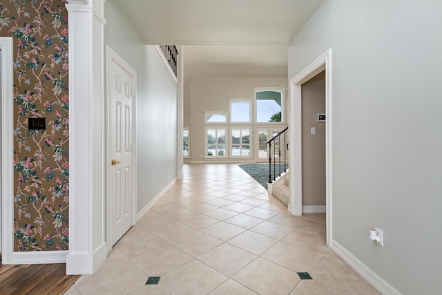 hallway with baseboards, stairway, and light tile patterned floors