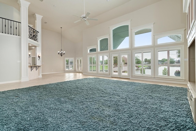 interior space featuring baseboards, high vaulted ceiling, ceiling fan with notable chandelier, and ornate columns