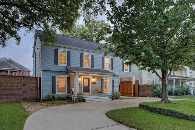 view of front of house featuring fence, a gate, a porch, and a front lawn