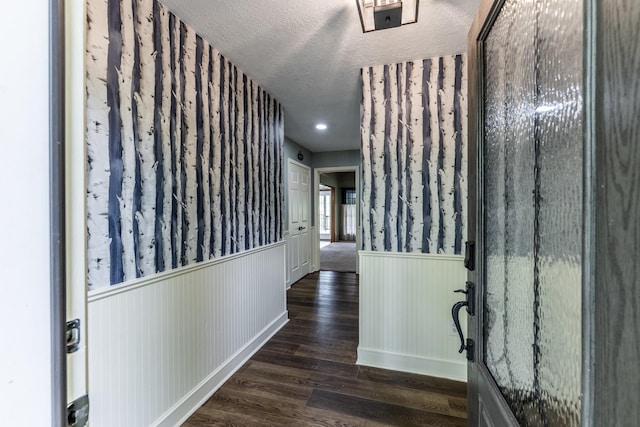 corridor featuring wainscoting, a textured ceiling, and dark wood-style floors