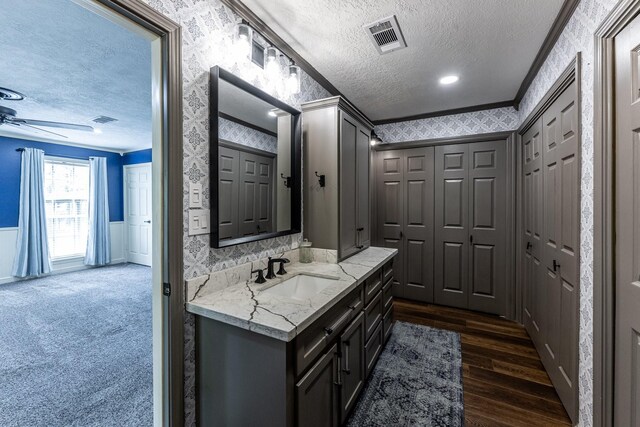 bathroom with crown molding, visible vents, wainscoting, and wallpapered walls