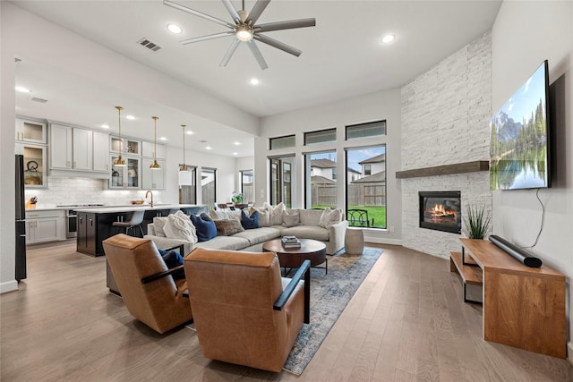 9010 Pleasant Cv, Missouri City, TX 77459 - living room featuring a stone fireplace, light wood-style flooring, visible vents, ceiling fan, and recessed lighting