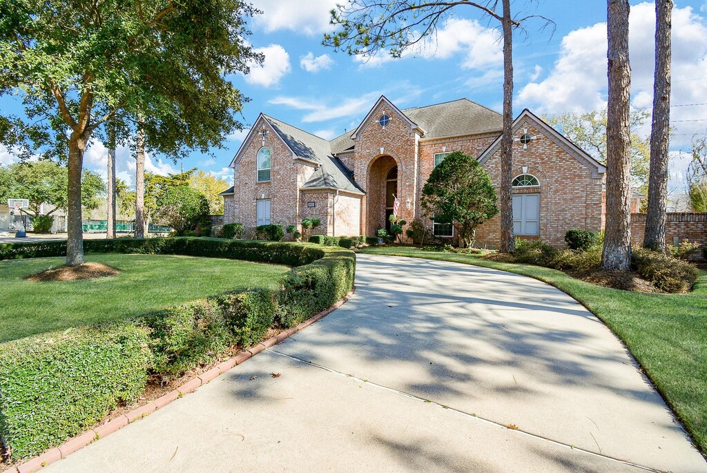 903 Bayou Parkway Ln, Houston, TX 77077 - view of front of property featuring a front lawn, brick siding, and concrete driveway
