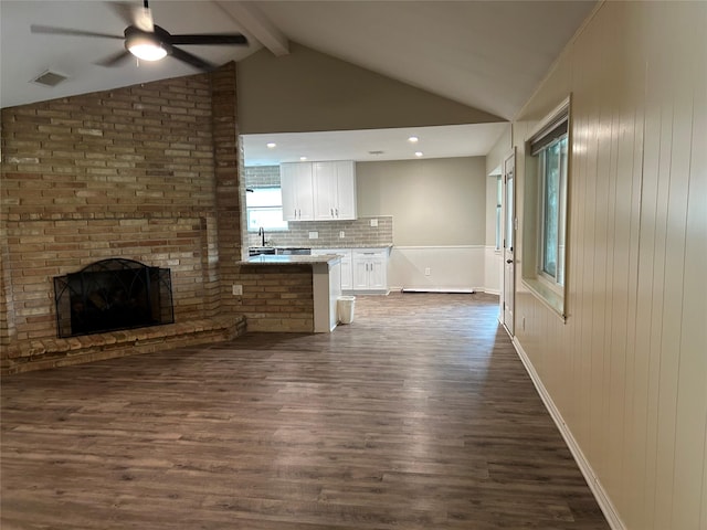 unfurnished living room featuring lofted ceiling with beams, ceiling fan, visible vents, a fireplace, and dark wood-style floors
