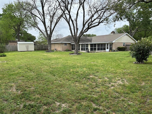 view of yard with an outdoor structure, a sunroom, a shed, and fence