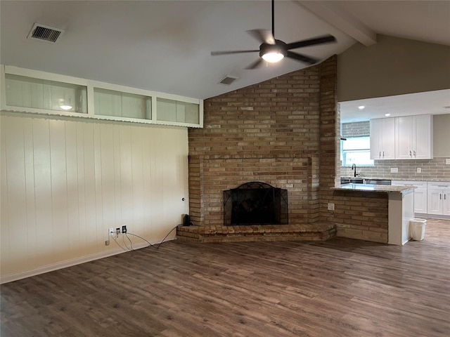 unfurnished living room with ceiling fan, dark wood-type flooring, visible vents, and vaulted ceiling with beams