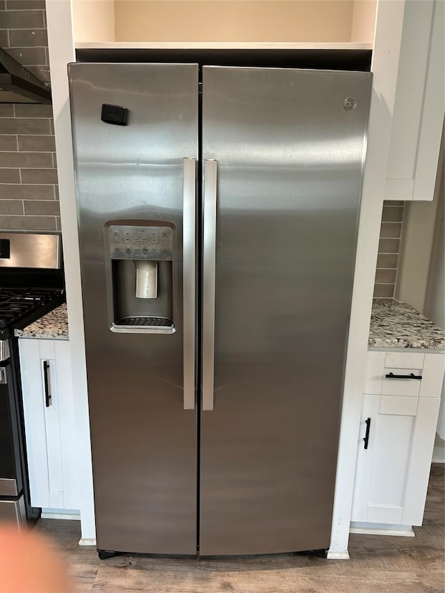 interior details featuring white cabinets, backsplash, appliances with stainless steel finishes, and light stone counters