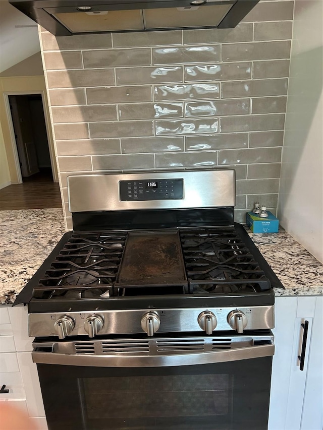 details featuring light stone countertops, decorative backsplash, and gas range