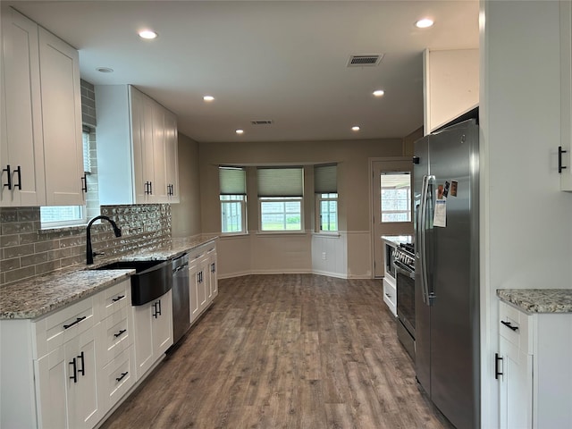 6018 Rena St, Houston, TX 77092 - kitchen with stainless steel appliances, wood finished floors, visible vents, a sink, and white cabinetry