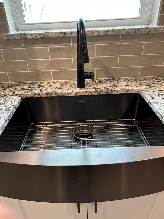 room details with a sink, backsplash, and light stone counters