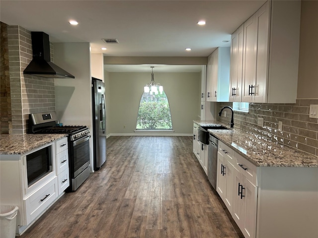 kitchen with wall chimney range hood, a sink, stainless steel appliances, dark wood-style flooring, and visible vents