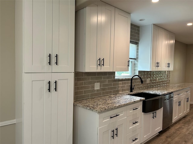 kitchen with a sink, dark wood-style flooring, recessed lighting, light stone countertops, and dishwasher