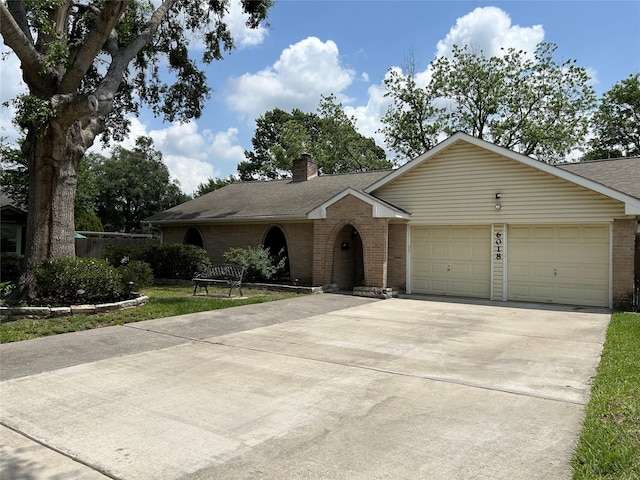 ranch-style home featuring driveway, a chimney, an attached garage, and brick siding