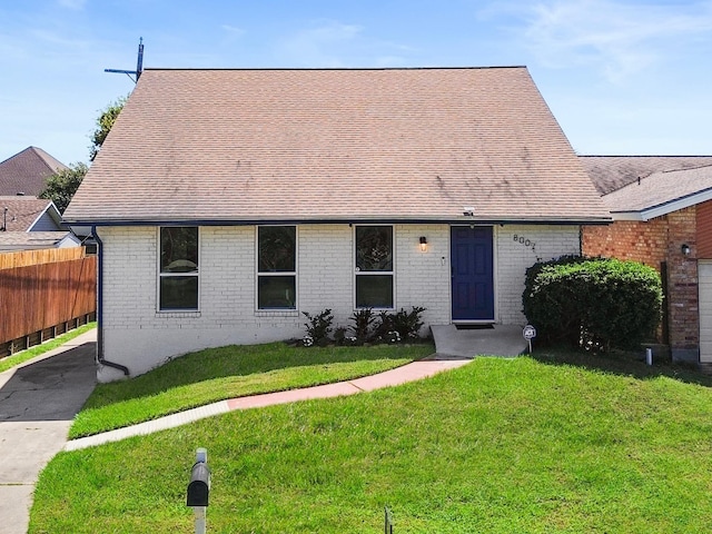 8007 Beluche Dr, Galveston, TX 77551 - view of front of home with a shingled roof, a front yard, fence, and brick siding