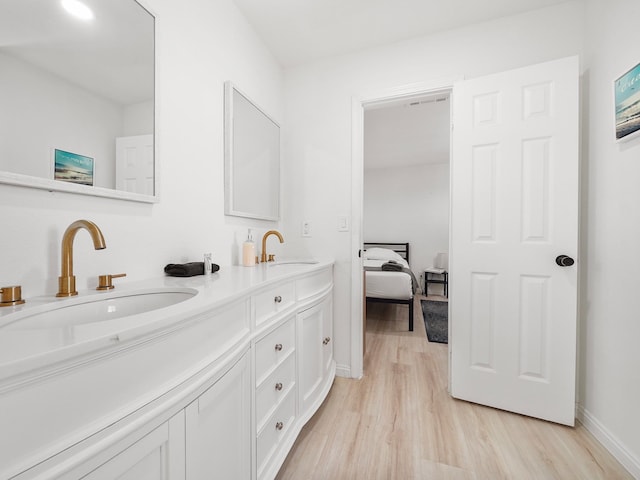8007 Beluche Dr, Galveston, TX 77551 - bathroom featuring double vanity, a sink, baseboards, and wood finished floors