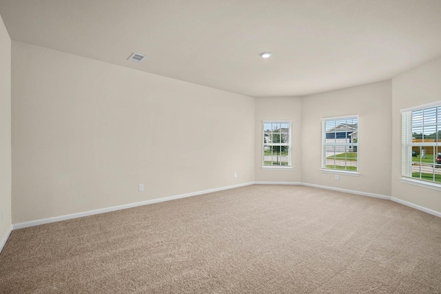unfurnished room with plenty of natural light, baseboards, light colored carpet, and visible vents
