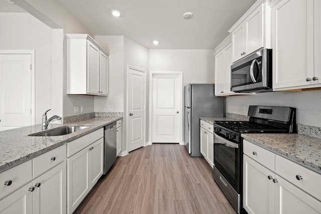 kitchen with light wood finished floors, a sink, white cabinets, and appliances with stainless steel finishes