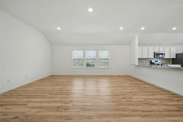 unfurnished living room with light wood finished floors, baseboards, vaulted ceiling, and recessed lighting
