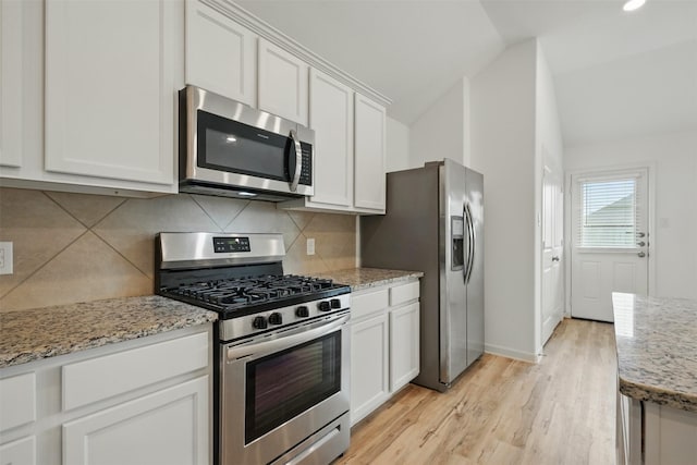 kitchen with white cabinetry, tasteful backsplash, lofted ceiling, stainless steel appliances, and light wood-style floors