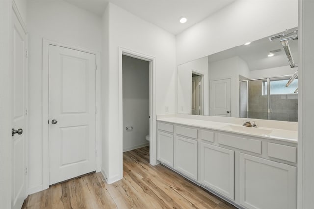 bathroom featuring vanity, toilet, a shower stall, visible vents, and wood finished floors