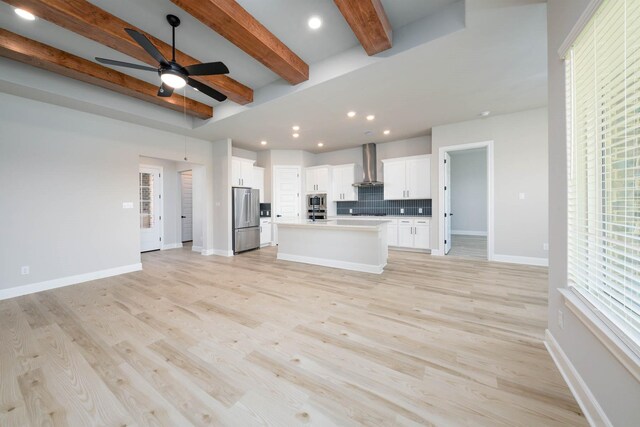 unfurnished living room with a ceiling fan, light wood-style floors, beamed ceiling, baseboards, and recessed lighting