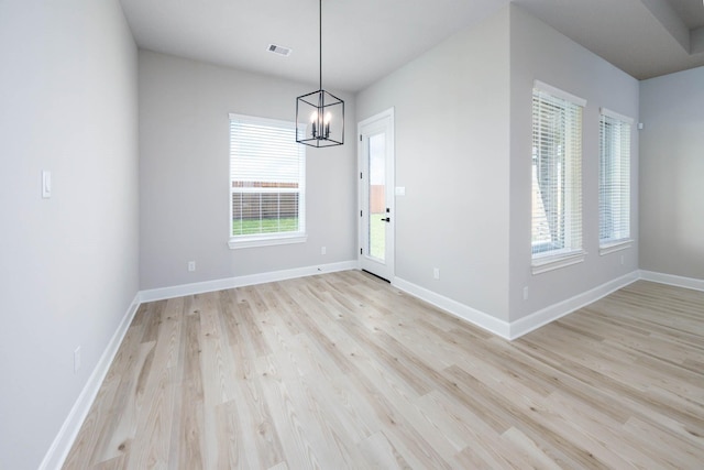 unfurnished dining area with baseboards, an inviting chandelier, visible vents, and light wood-style flooring