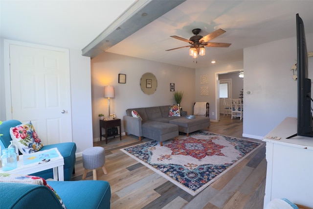 living room featuring baseboards, a ceiling fan, and light wood finished floors