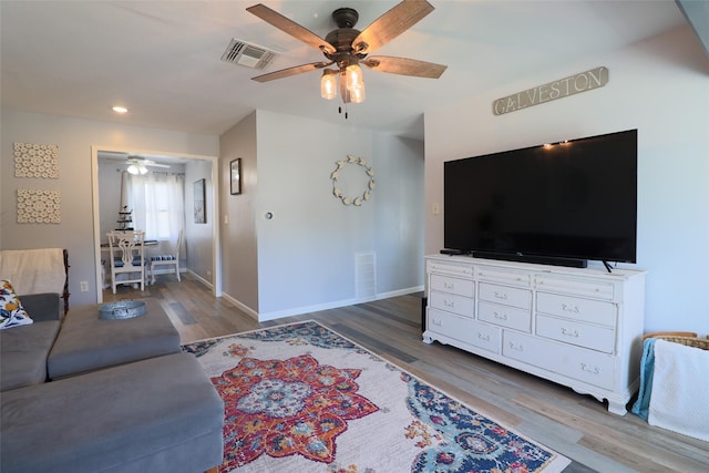 living room featuring baseboards, visible vents, wood finished floors, and ceiling fan