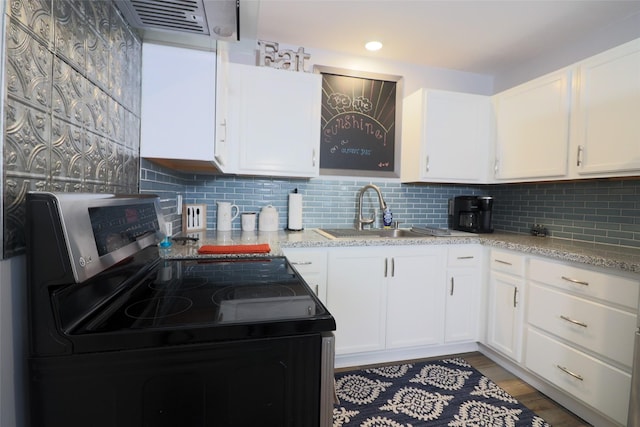 kitchen with white cabinetry, backsplash, a sink, stainless steel range with electric cooktop, and light wood-style flooring
