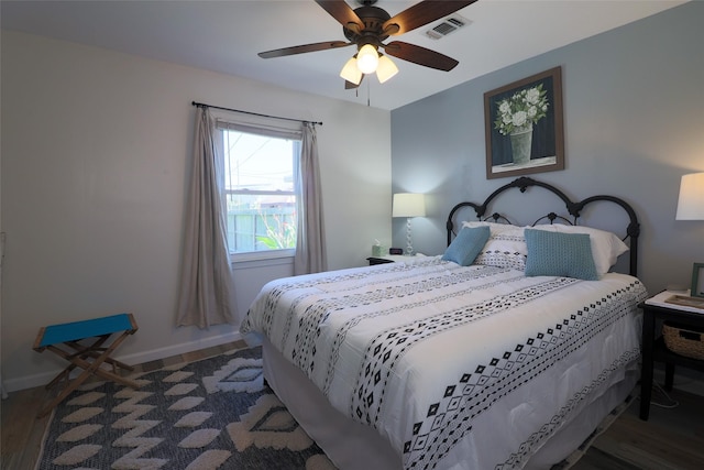 bedroom featuring baseboards, visible vents, wood finished floors, and a ceiling fan