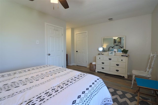 bedroom with a ceiling fan, dark wood-style floors, baseboards, and visible vents