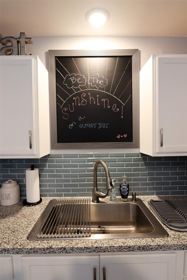 details featuring white cabinetry, backsplash, and a sink