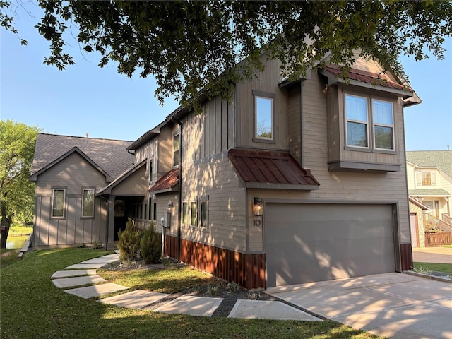 view of front of house featuring board and batten siding, metal roof, a front yard, concrete driveway, and an attached garage