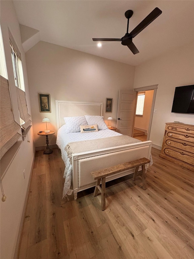 bedroom featuring a ceiling fan, lofted ceiling, wood finished floors, and baseboards