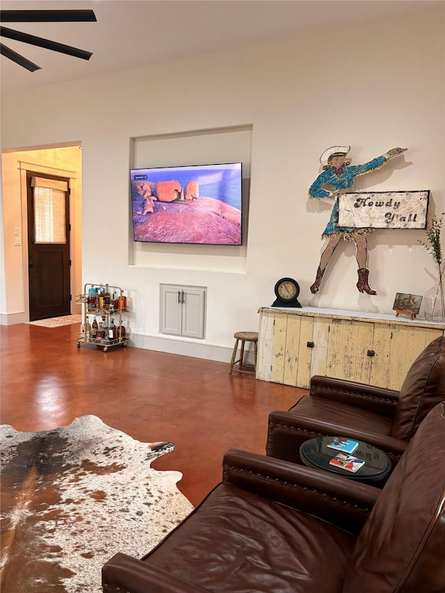 living area featuring finished concrete floors, ceiling fan, and baseboards