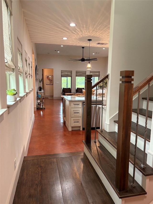 hallway featuring stairway, visible vents, baseboards, dark wood-style flooring, and recessed lighting