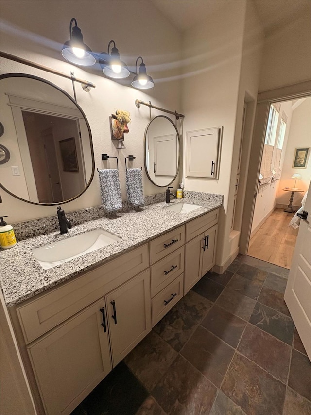 full bathroom featuring stone finish floor, double vanity, and a sink