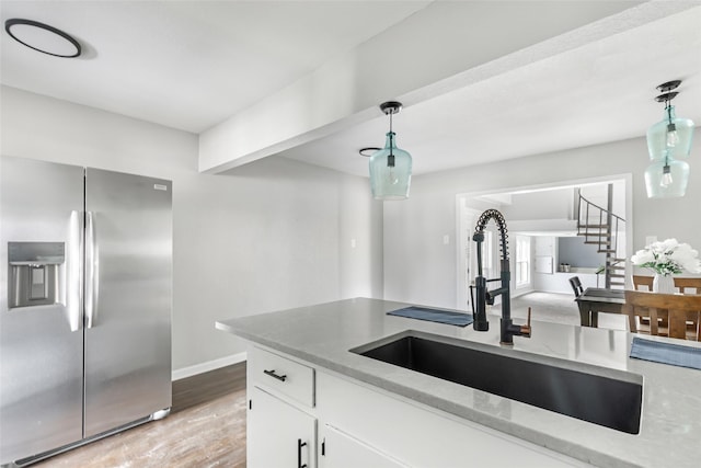 11610 Lane St, Houston, TX 77029 - kitchen featuring decorative light fixtures, white cabinetry, stainless steel fridge, and a sink