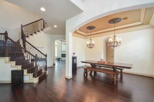 dining room with arched walkways, stairway, baseboards, a raised ceiling, and a chandelier