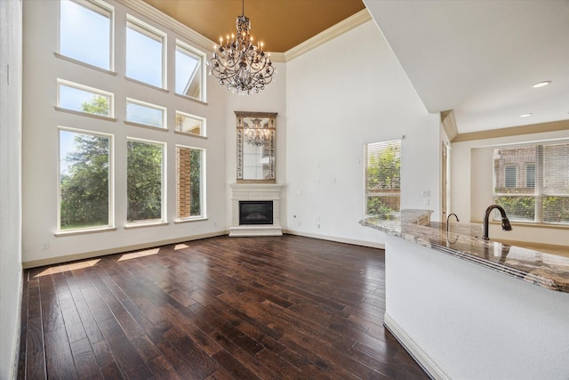27 Tioga Pl, The Woodlands, TX 77375 - unfurnished living room with a chandelier, plenty of natural light, a towering ceiling, a glass covered fireplace, and baseboards