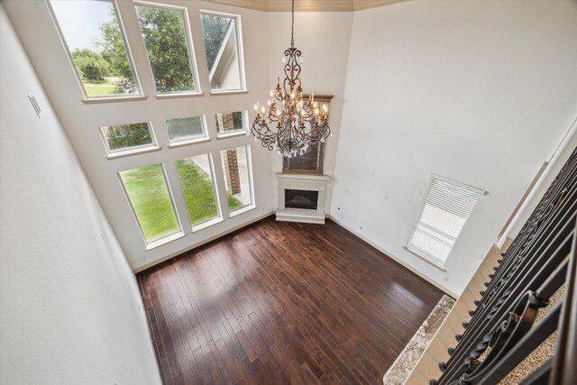 27 Tioga Pl, The Woodlands, TX 77375 - unfurnished living room featuring a towering ceiling, a chandelier, plenty of natural light, a glass covered fireplace, and dark wood-type flooring